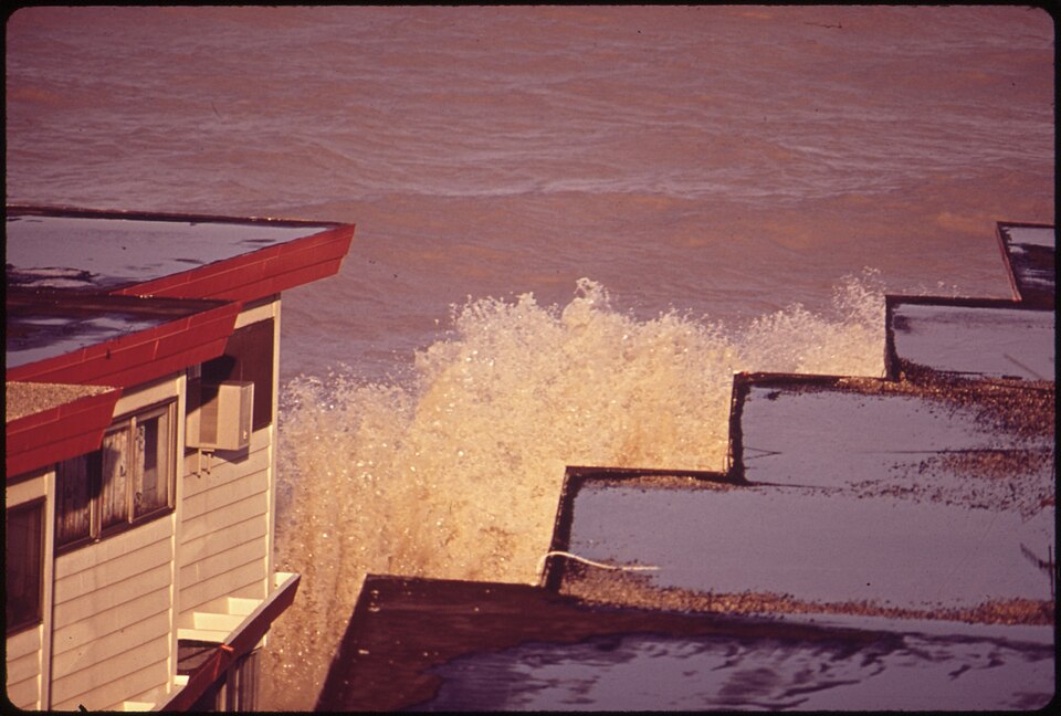 Waves breaking against shoreline buildings protected by a seawall.